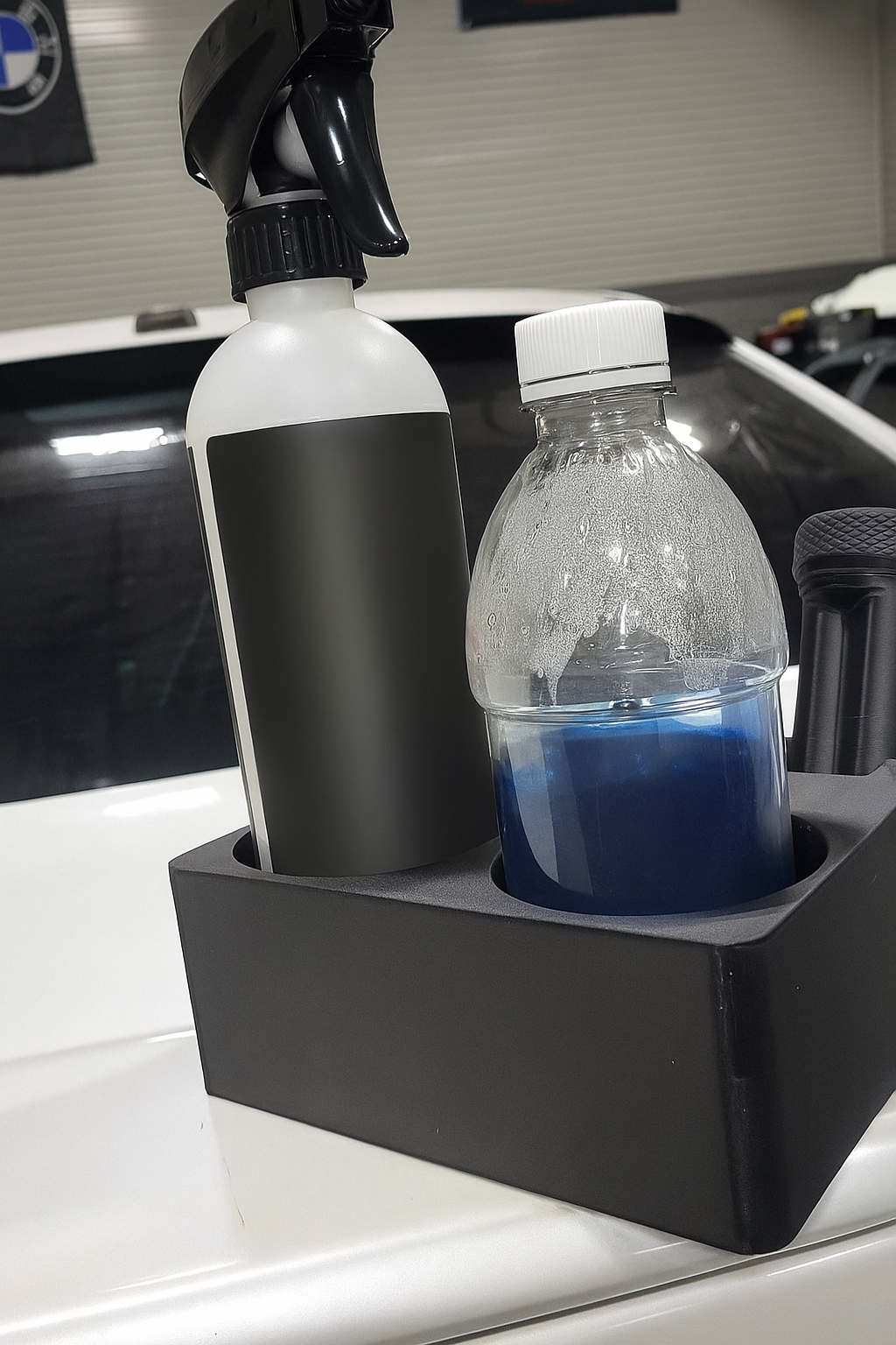 BMW E30 cupholders front view ontop of a white car with a water bottle and a spray bottle in the slots bottles are blank with no logos