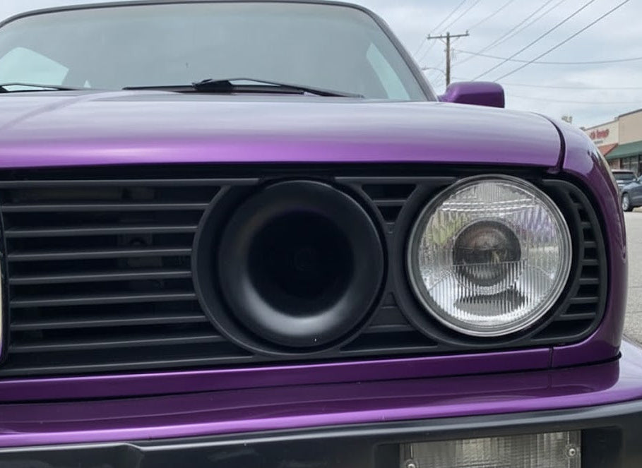 Close-up of a purple car's front grille with a visible duct.